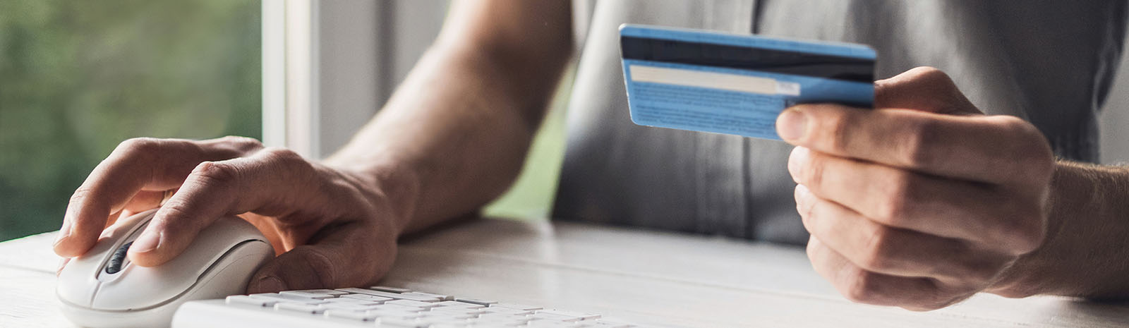 Hands holding credit card while using a computer