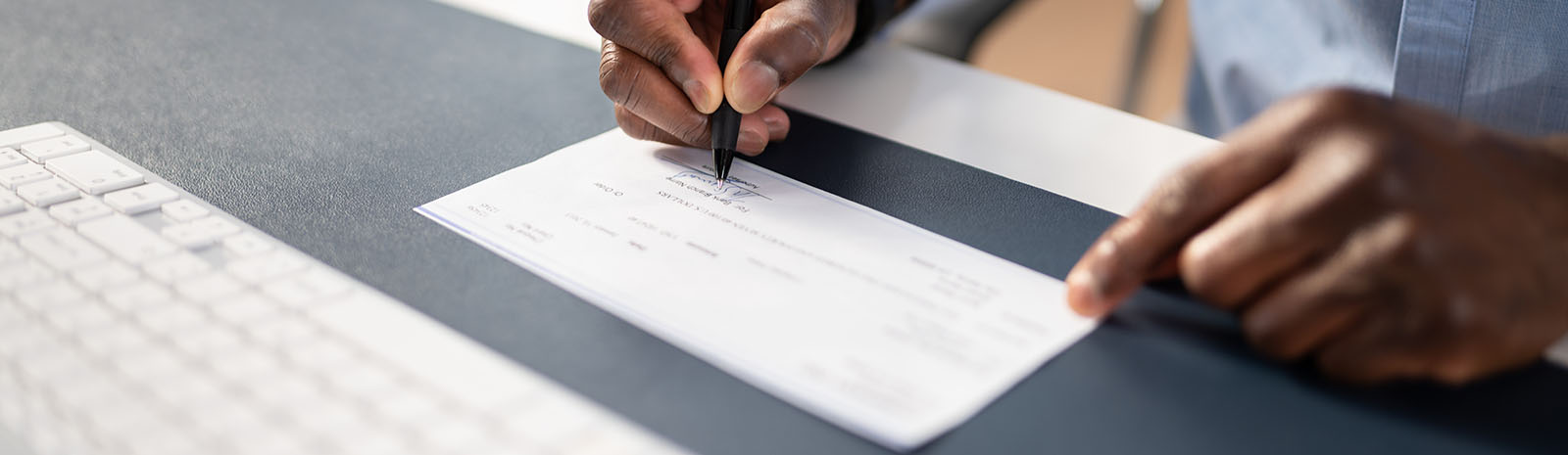 Man's hands writing a check at desk